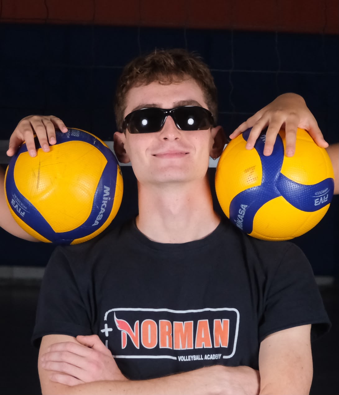 Burak Çetintaş, Norman tişörtüyle ve omuzlarında iki voleybol topuyla.